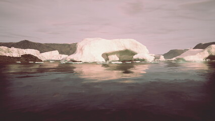 Fototapeta premium A scenic view showcases massive icebergs drifting in tranquil arctic waters, reflecting the gentle sunlight. The surrounding mountains create a serene and beautiful atmosphere.