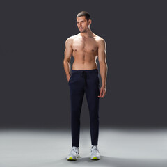 Fototapeta premium athletic male model standing in studio, showing muscular back, shoulders, and fit physique against dark background.