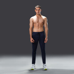 Fototapeta premium athletic male model standing in studio, showing muscular back, shoulders, and fit physique against dark background.