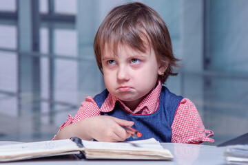 Annoyed child sitting at desk with notebook, puffing cheeks and rolling eyes — funny concept of office frustration and work overload.