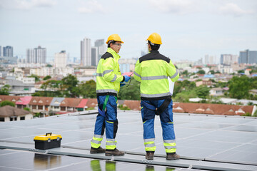 Back view engineers on a rooftop, inspecting a solar panel installation, with a cityscape in the...