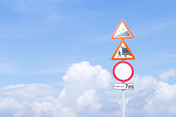 Aluminum warning sign drive slowly because road is steep. No trucks allowed to pass through Length over 7m. Regulatory signs for vehicular traffic. With blue sky cloud white is background.