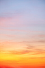 Sunset or sunrise sky with a vibrant gradient of orange, gold, and soft blue. Clear atmosphere with wispy clouds. Peaceful, natural light background. hope, freedom, new day Concepts, Vertical