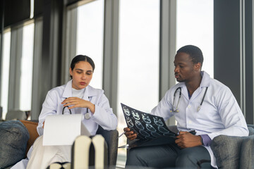 Two doctors discussing patient medical reports and radiology x-ray scans in healthcare facility hospital, concept teamwork in healthcare, diagnosis collaboration and clinical analysis case conference