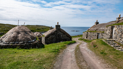 Traditional stone walled buildings with thatched roofs on the rugged Scottish coast © Susan Halewood
