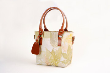 Beautiful leather bag for women with floral pattern in cream color isolated on white background