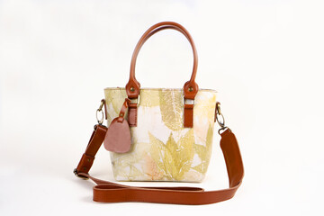 Beautiful leather bag for women with floral pattern in cream color isolated on white background