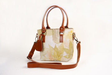 Beautiful leather bag for women with floral pattern in cream color isolated on white background