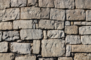 background, stone wall structure, constructed from light-colored stones of varying sizes, with some stones featuring darker veins or inclusions