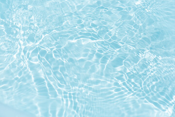 Blue water with ripples on the surface. Defocus blurred transparent blue colored clear calm water surface texture with splashes and bubbles. Water waves with shining pattern texture background.