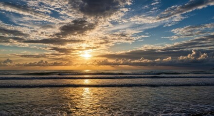 Obraz premium Golden sunset reflects on ocean waves under dramatic, textured clouds