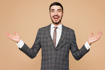 Young shocked surprised happy successful employee business man corporate lawyer wear classic formal grey suit shirt tie work in office spread hands isolated on plain beige background studio portrait.