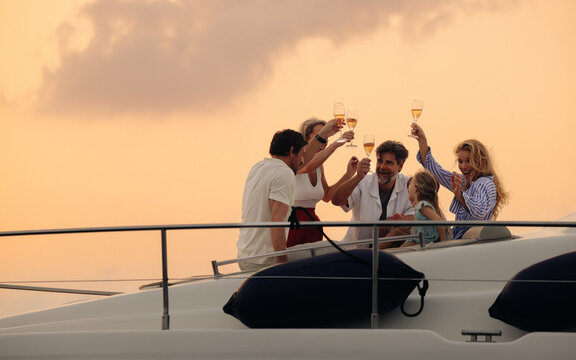 Wealthy family toasting to health and happiness on a luxury boat at sunset