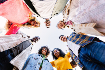 Low angle view of young people in circle looking at camera. Smiling portrait of millennial friends...