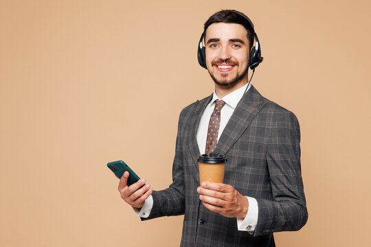 Employee operator business man in set microphone headset for helpline assistance work at call center office hold use mobile cell phone drink coffee isolated on plain beige background studio portrait. - Powered by Adobe
