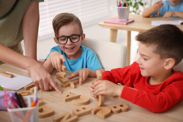 Obraz premium Little boys having lesson with teacher at wooden desk in elementary school, closeup