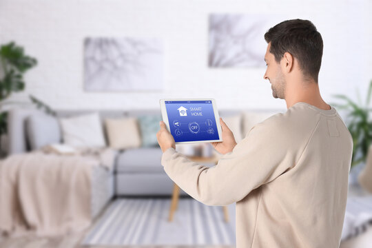 Man using smart home app on tablet computer to control house features
