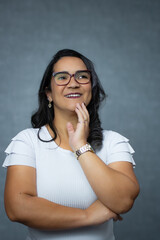 Mature adult woman with hand on chin, wearing white shirt an eyeglasses, looking upwards. Studio portrait with copy space ideal for planning, thinking, daydreaming and career opportunities.