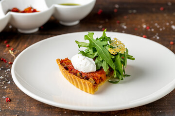Mini tomato tart topped with burrata and peppery arugula garnish