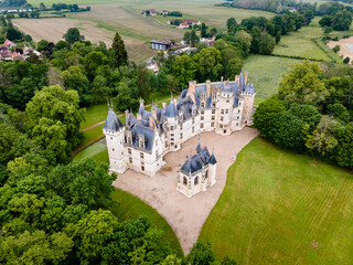 Aerial shot of Château de Meillant in Meillant, France, showing the château and its clear-standing chapel amid lush green fields and scattered trees.

