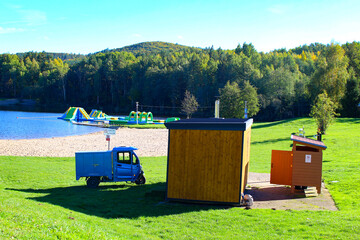 Bright sunny day at a lakeside park featuring inflatable attractions and wooden