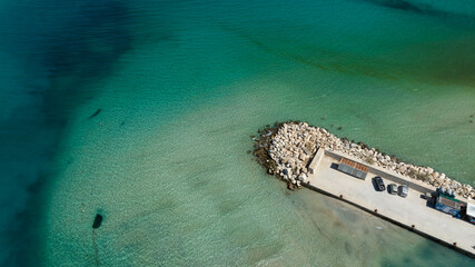 Aerial view of a pier in a turquoise sea.
