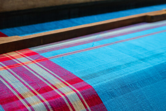 Cotton saree fabric is being woven on a handloom. Traditional man made saree using a handloom. Blue saree with pink border.