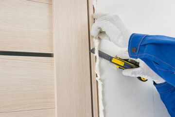 the master's hands use a stationery knife to cut off the dried mounting foam, close-up