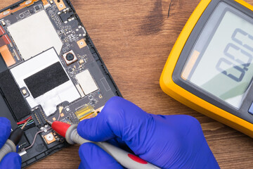 To repair the gadget's display, the master uses a voltage measuring device.