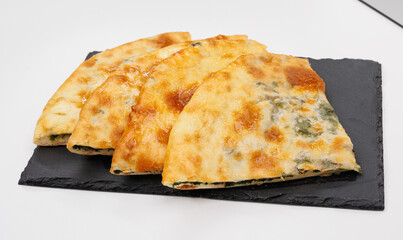 Georgian Khachapuri Pkhlovana With Herbs and Melted Cheese On White Surface