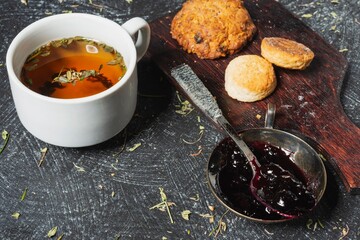 Still life - blueberry jam and herbal tea on the table. Sweet food on a dark background