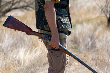A hunter with a gun in camouflage clothing. A gentleman with a gun, medium shot, unrecognizable.