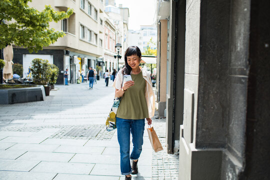 Young woman walking in the city and using a phone