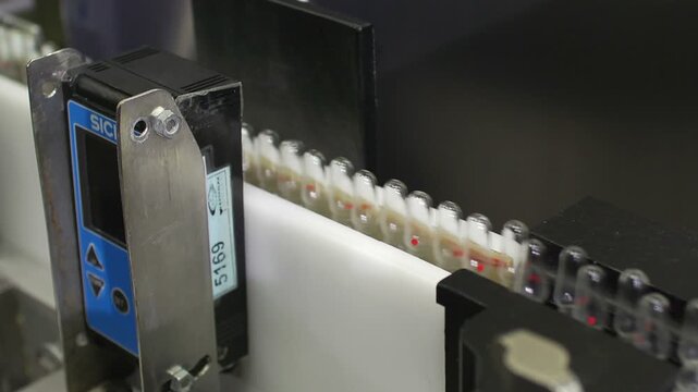 High-definition footage of an automated cleanroom assembly where glass ampoules are washed, filled with injectable medication, sterilized, and hermetically sealed. Showcases precision robotics, strict