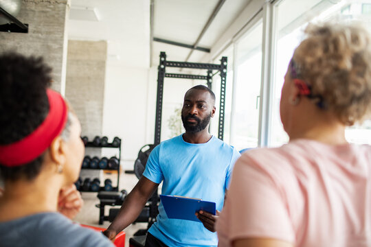 Young trainer working with clients in a gym