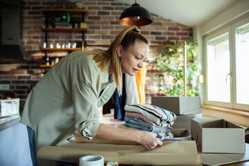 Young adult woman packing clothes at home