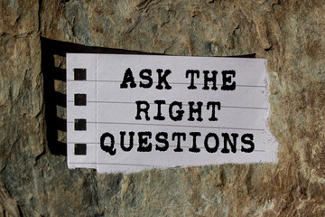 Ask The Right Questions message written on ripped torn lined paper piece on stone background....