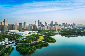 Aerial view of the modern downtown cityscape with a large stadium and lush green park by the water in Shenzhen.
