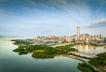 Modern financial district skyline with green parkland and coastal development during the day in Shenzhen.