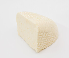 A pale block of cheese with a soft, textured rind sits on a bright white surface