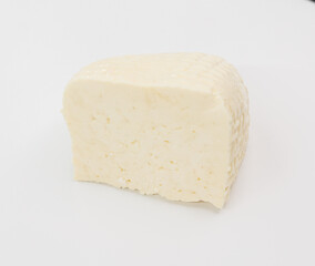 A pale block of cheese with a soft, textured rind sits on a bright white surface