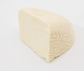 A pale block of cheese with a soft, textured rind sits on a bright white surface