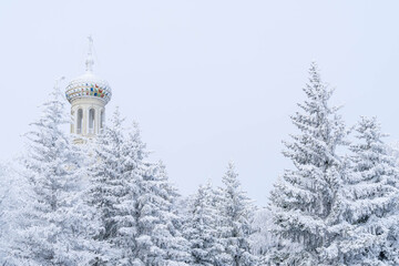 Fototapeta premium Dome of the Kazan Cathedral above snow covered fir trees in Stavropol, Russia, during a cold winter morning. 