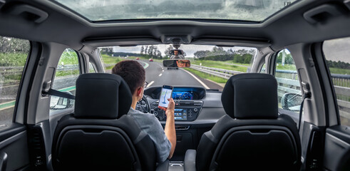 Driver holding phone for navigation. Modern travel vibe.