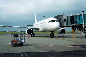 Obraz premium Charter airline airplane preparing for flight on airport runway with connected jet boarding bridge