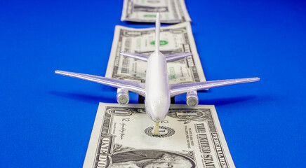Model airplane on dollar bills representing travel expenses in the travel industry
