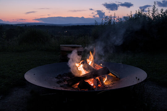 round circle fire pit burning logs at sunset in catskills mountains catskill upstate new york travel camping leisure scenic nature landscape flame wood wooden log warmth cozy outdoor adventure