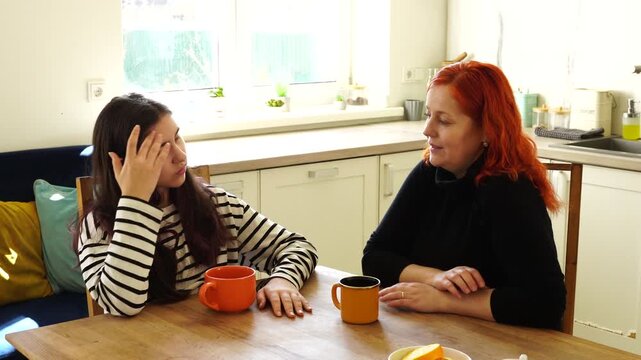 Mother with daughter communicate at the kitchen
