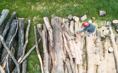 Lumberjack with a chainsaw cutting trees in the forest. Preparing firewood for winter. Top down view. Aerial view from drone
