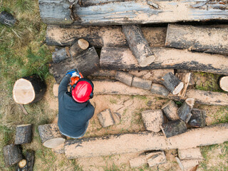 Lumberjack with a chainsaw cutting trees in the forest. Preparing firewood for winter. Top down view. Aerial view from drone
